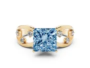 Fancy Blue Princess Cut Diamond Solitaire Ring Set in Yellow gold with Side Stones on Criss-Cross Band and Prong Setting