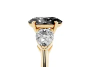 Fancy Black Three-Stone Oval Cut Diamond Ring Set in Yellow gold with Pear Side Stones and Prong Setting