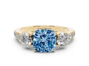 Fancy Blue Cushion Cut Diamond Three-Stone Ring Set in Yellow gold with Round Side Stones and Delicate Pavé Band