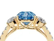 Fancy Blue Cushion Cut Diamond Three-Stone Ring Set in Yellow gold with Round Side Stones and Delicate Pavé Band