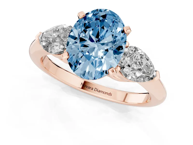 Fancy Blue Three-Stone Oval Cut Diamond Ring Set in Rose gold with Pear Side Stones and Prong Setting